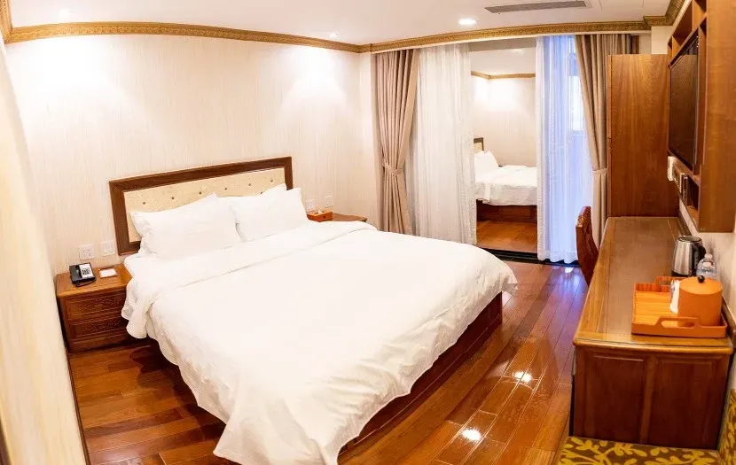 Hotel bedroom with a bed, desk, and view into another room.