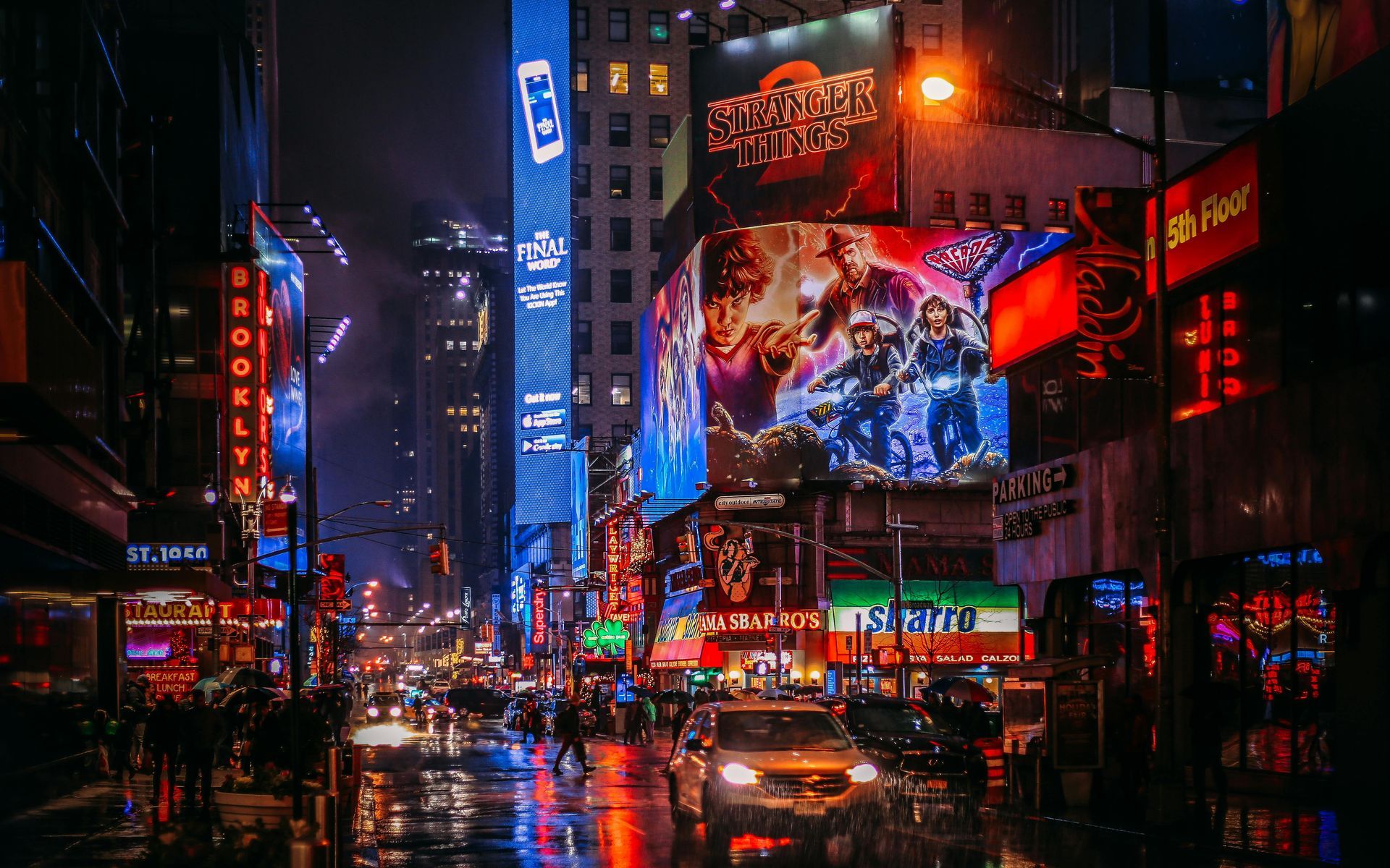 Bright neon lights illuminate Times Square at night; a busy street with cars and pedestrians.