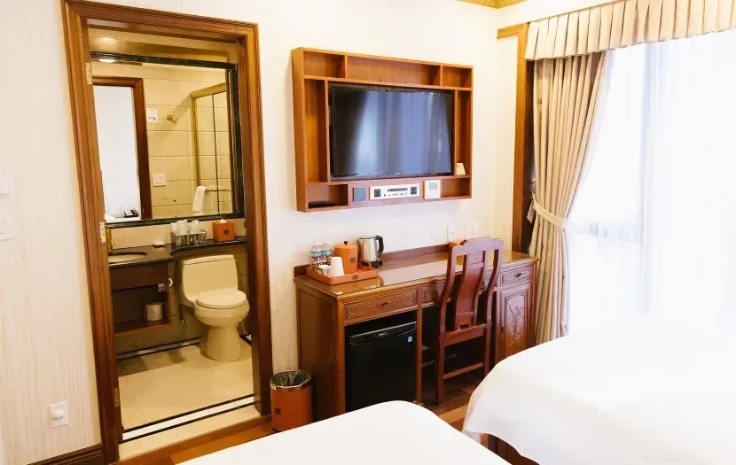 Hotel room interior with two beds, desk, TV, and bathroom visible.