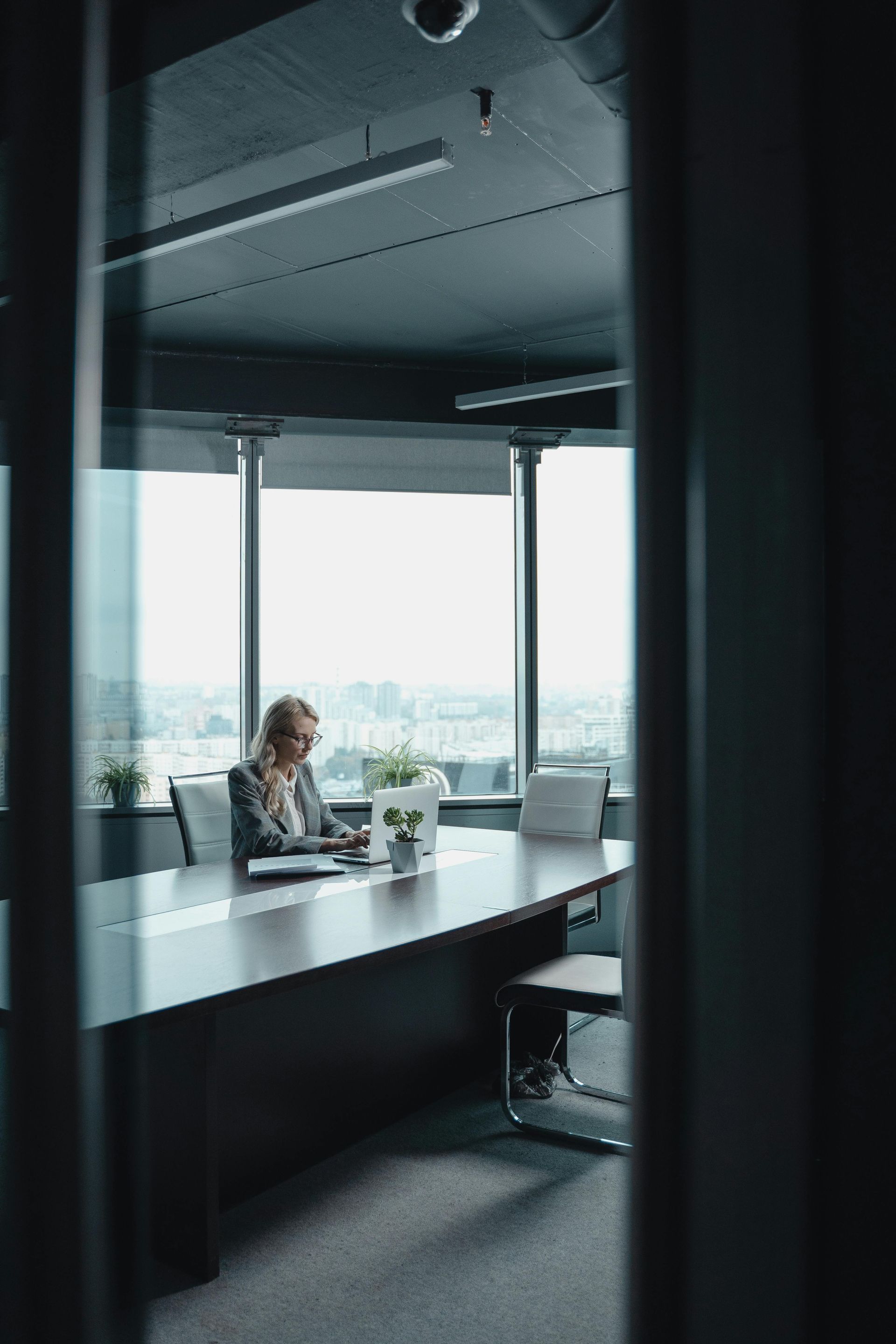 Person working alone at a desk in a modern office with large windows and city view