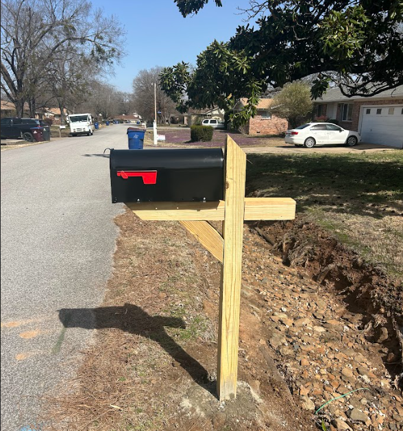 A mailbox on a wooden post next to a road