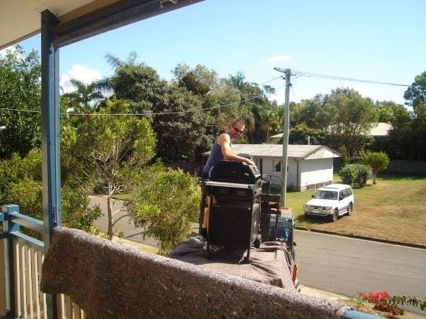 A Man is Sitting on the Roof of a Truck — Armstrong Removals in Brisbane, QLD
