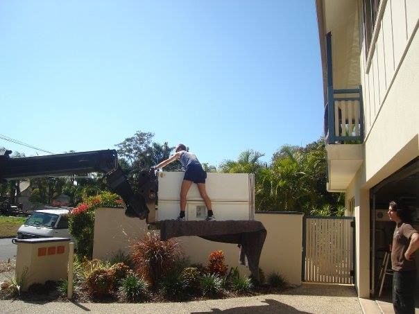 A Woman Is Standing on Top of A White Box Being Lifted by A Crane — Armstrong Removals in Ninderry, QLD