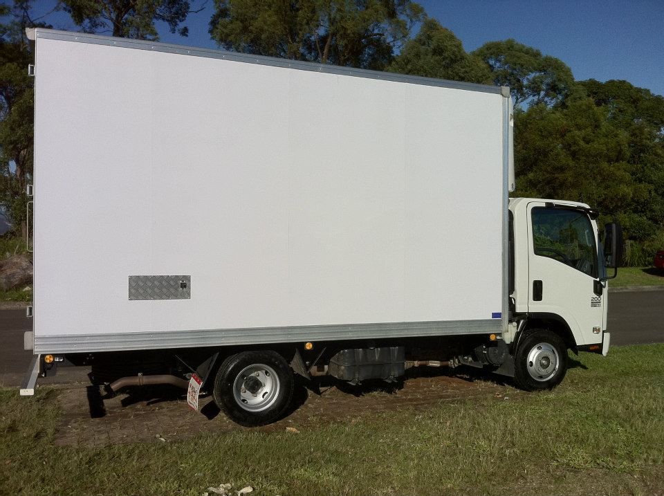 A White Truck Is Parked in The Grass on The Side of The Road — Armstrong Removals in Ninderry, QLD