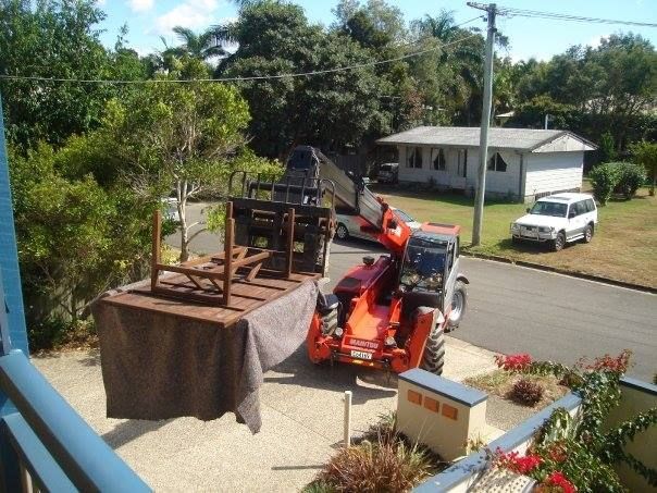 A Tractor Is Lifting a Table and Chairs in A Driveway — Armstrong Removals in Ninderry, QLD