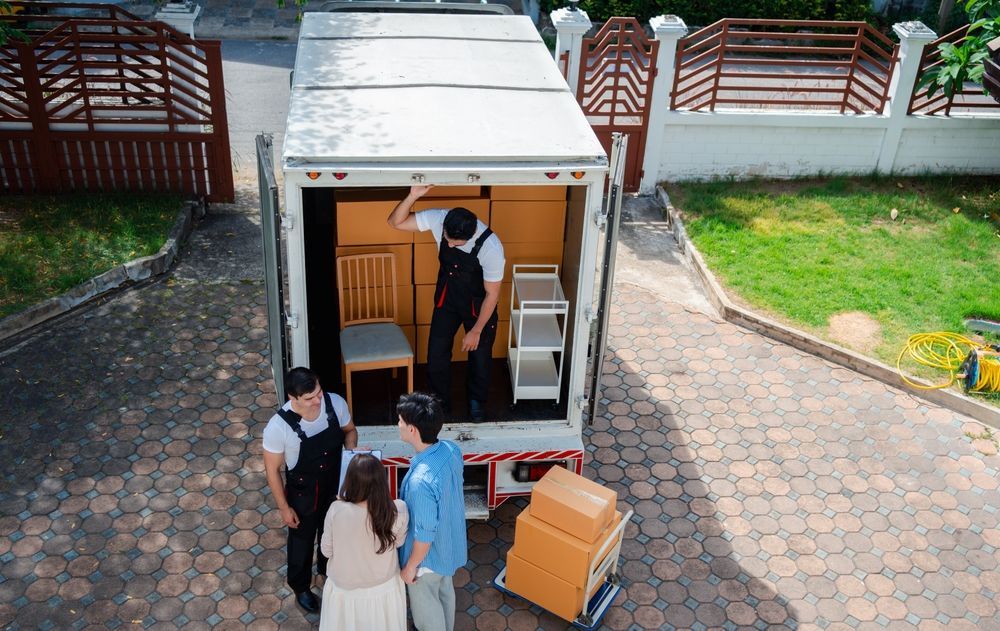 A Group Of People Are Standing In Front Of A Moving Truck — Armstrong Removals in Toowoomba, QLD