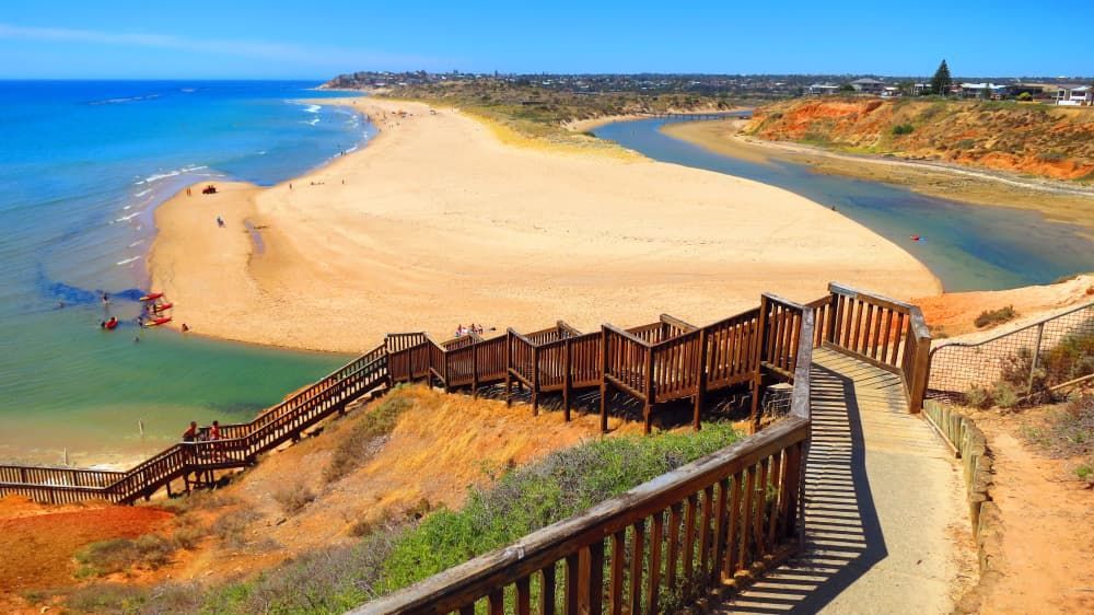 A Wooden Walkway Leading to A Beach Next to A River — Armstrong Removals in Adelaide, QLD