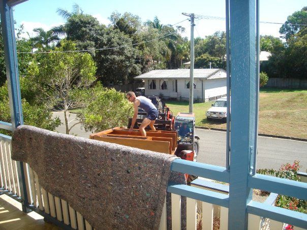 A Man in A Blue Shirt Is Standing in The Back of A Truck — Armstrong Removals in Ninderry, QLD