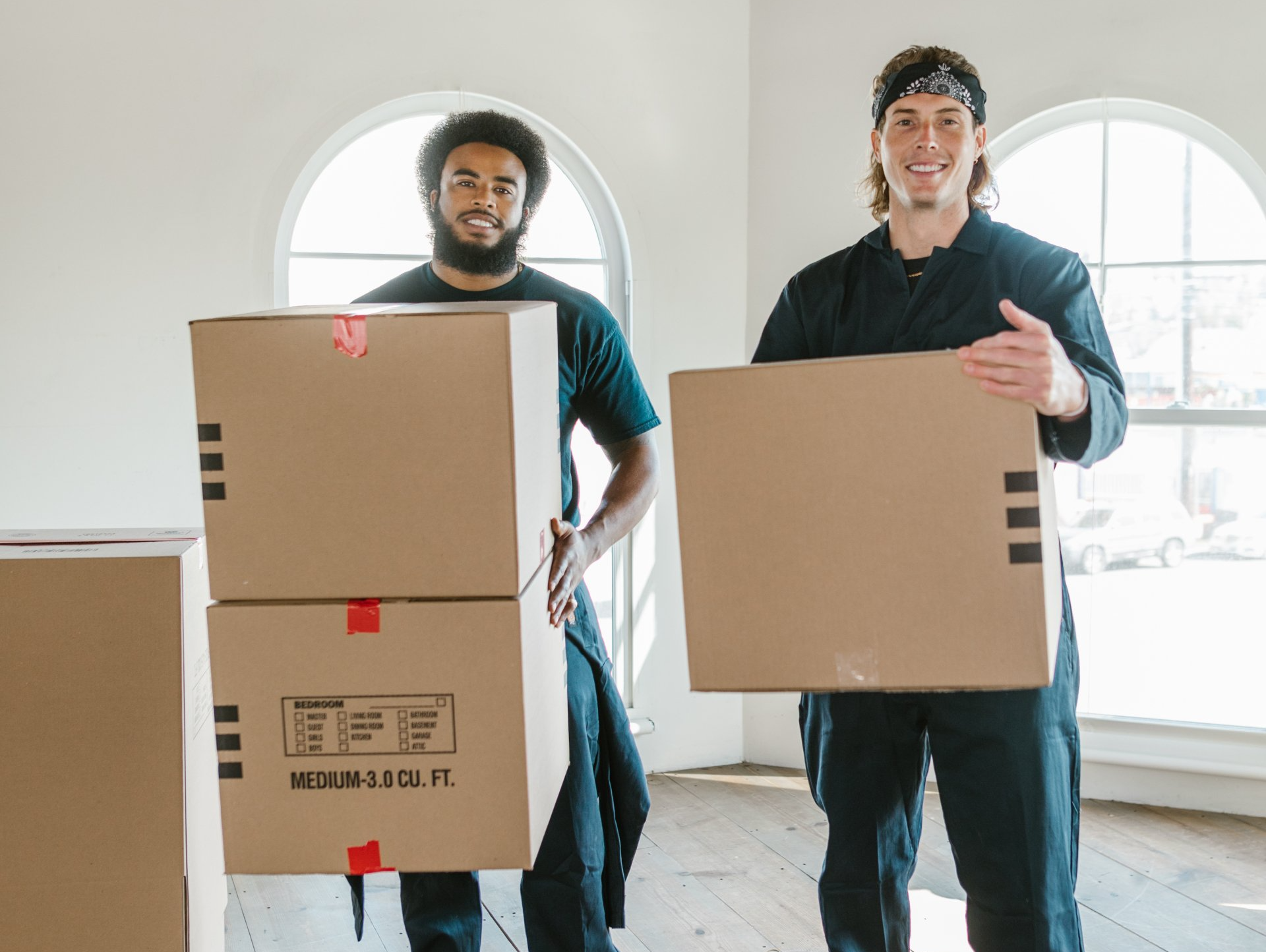 Two Men Are Carrying Cardboard Boxes in A Room — Armstrong Removals in Ninderry, QLD