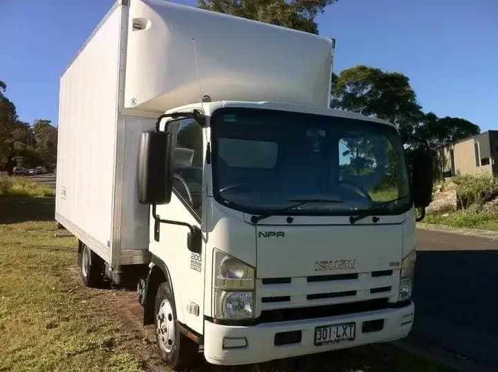 A White Isuzu Truck Is Parked on The Side of The Road — Armstrong Removals in Ninderry, QLD