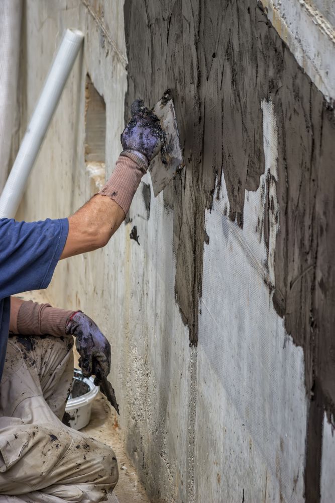 A Man is Plastering a Wall With a Trowel — Legend Waterproofing In Gosford, NSW