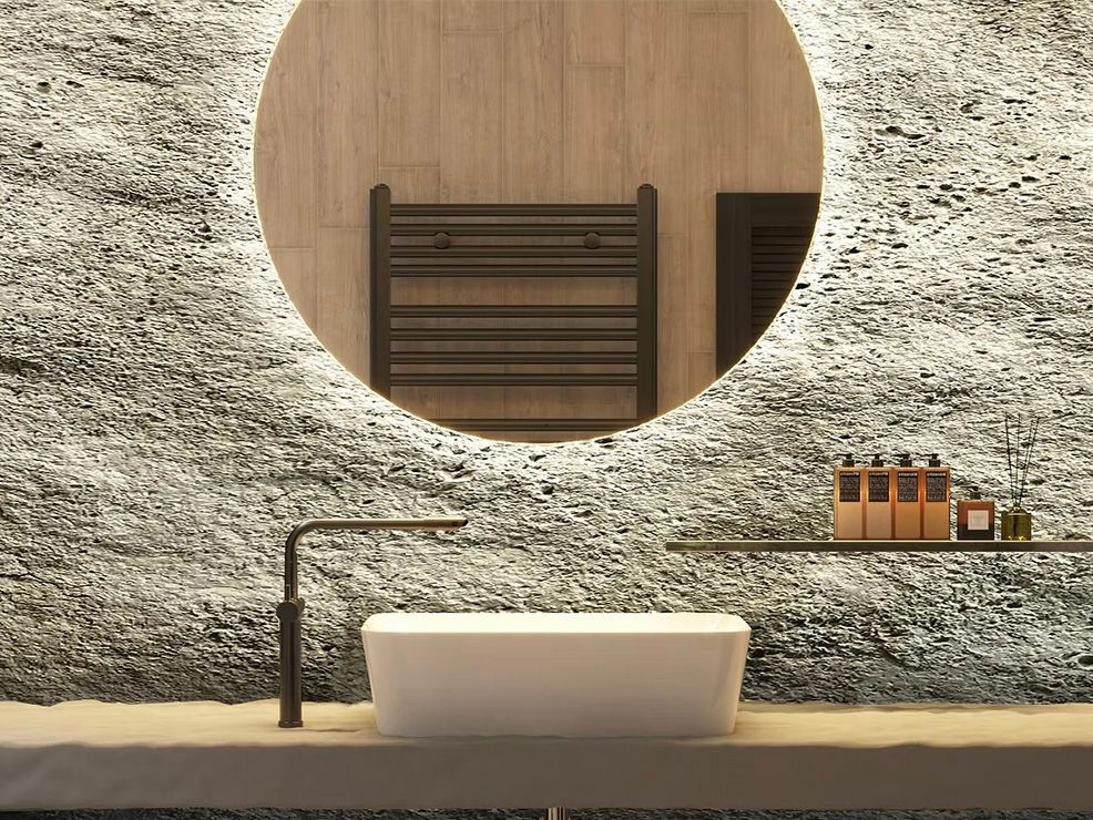 Modern bathroom with a white sink, round mirror, and textured gray wall.