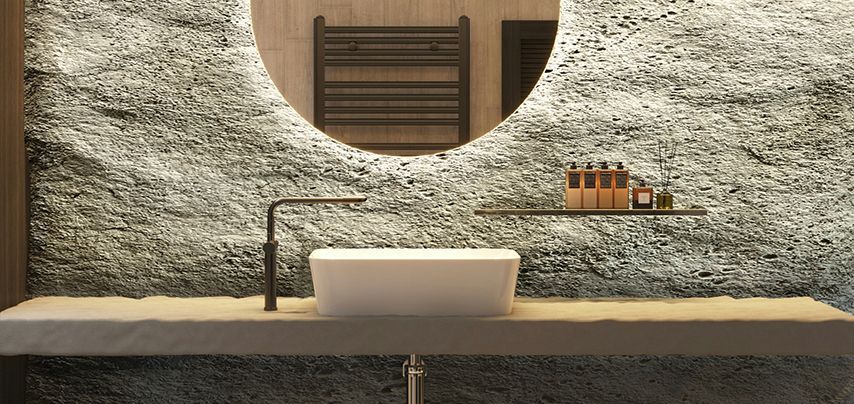 Bathroom with a white sink, black faucet, and round mirror set into a textured gray wall.