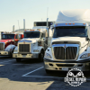 A row of semi trucks are parked in a parking lot waiting to get repaired by diesel repair denver.