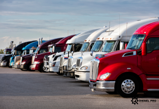 A row of semi trucks are parked in a field in Colorado.