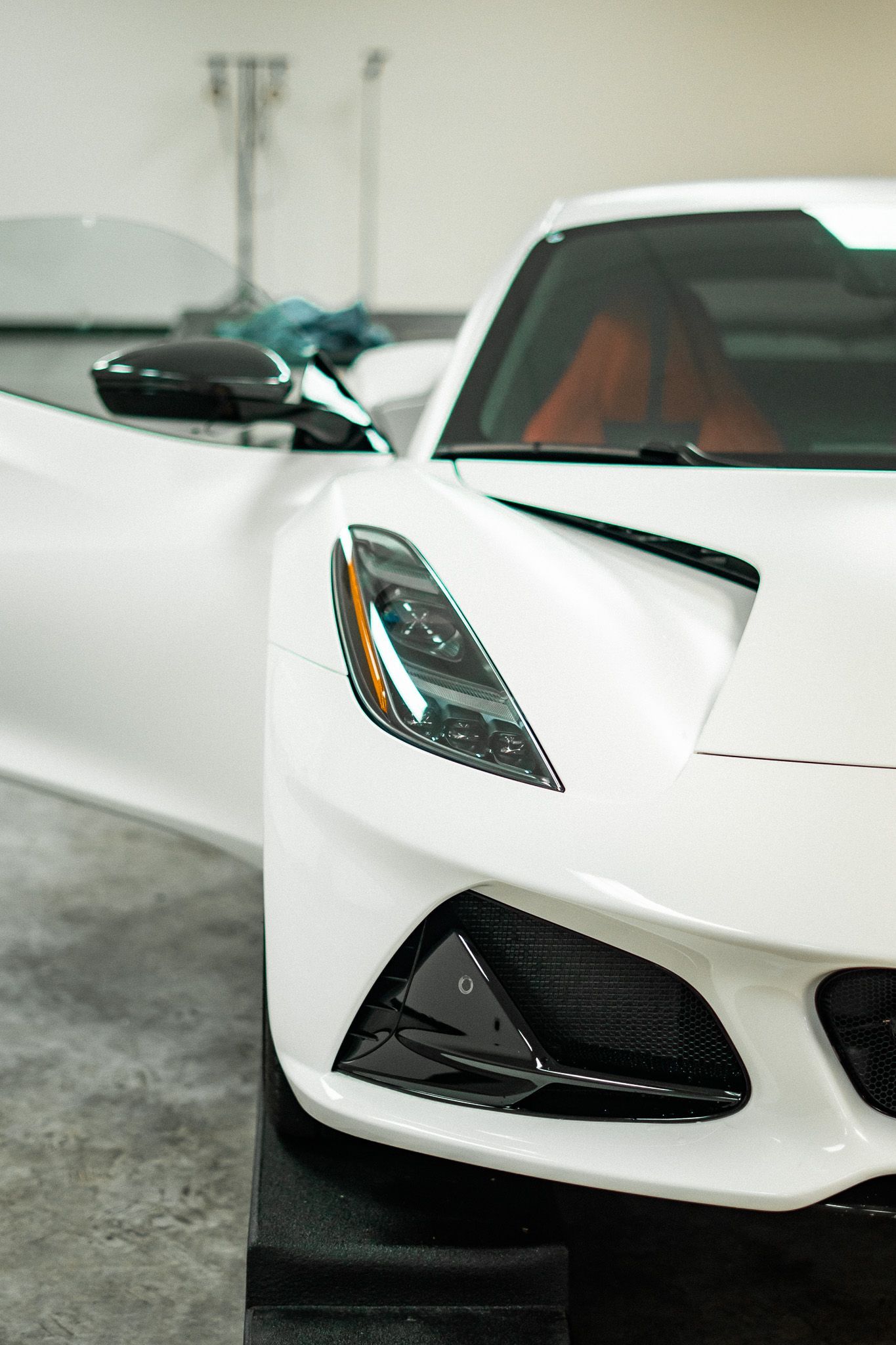 White sports car with an open door, parked in a garage.