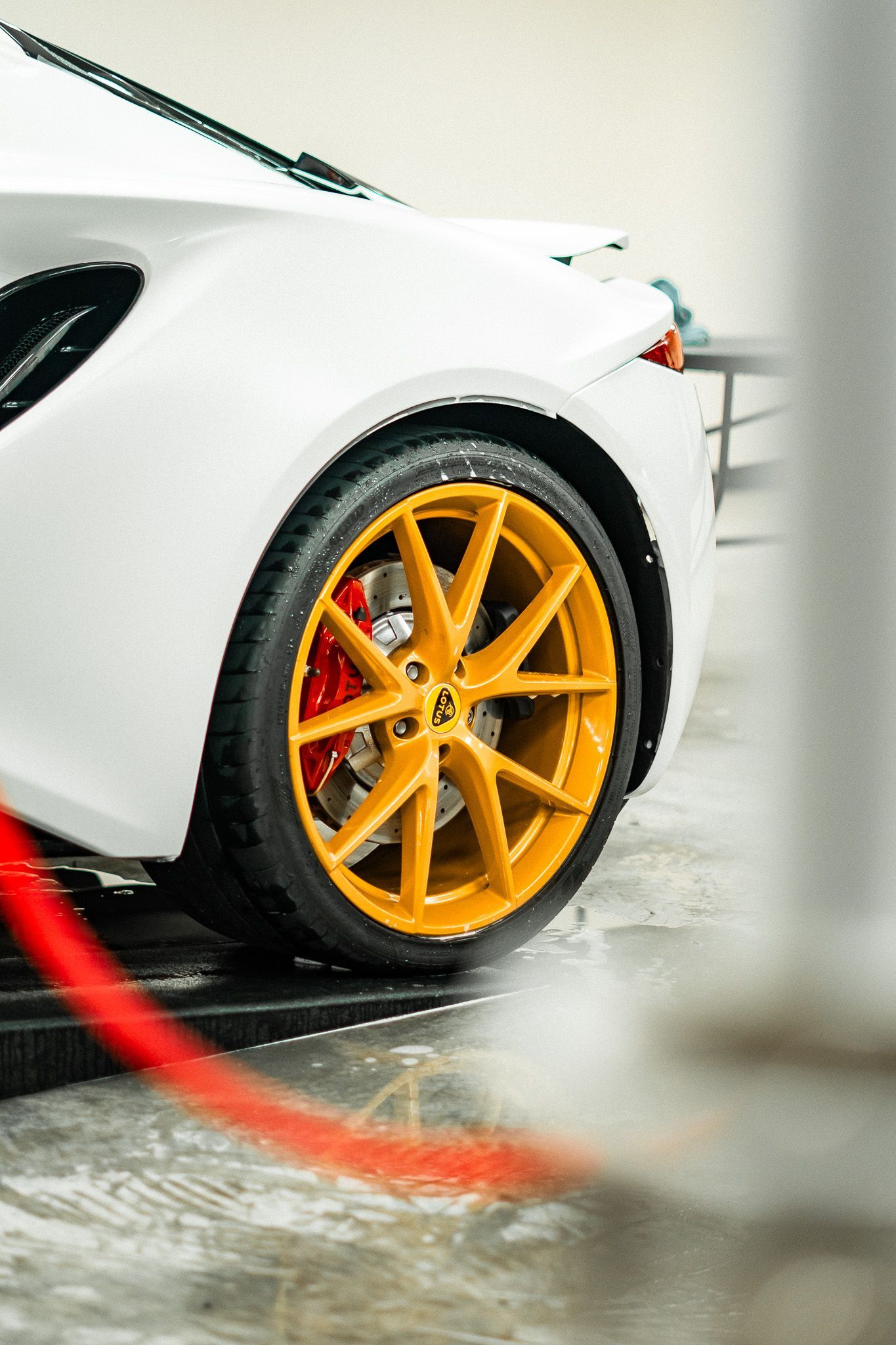 White car with gold rims, red brake calipers, at a car wash.