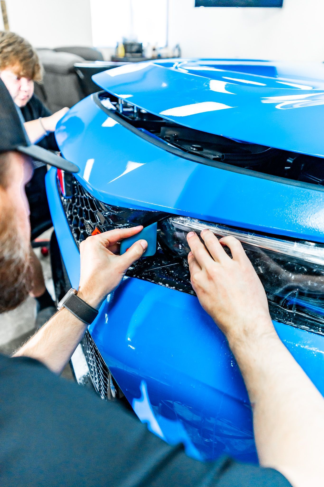 A man is working on the front of a car.