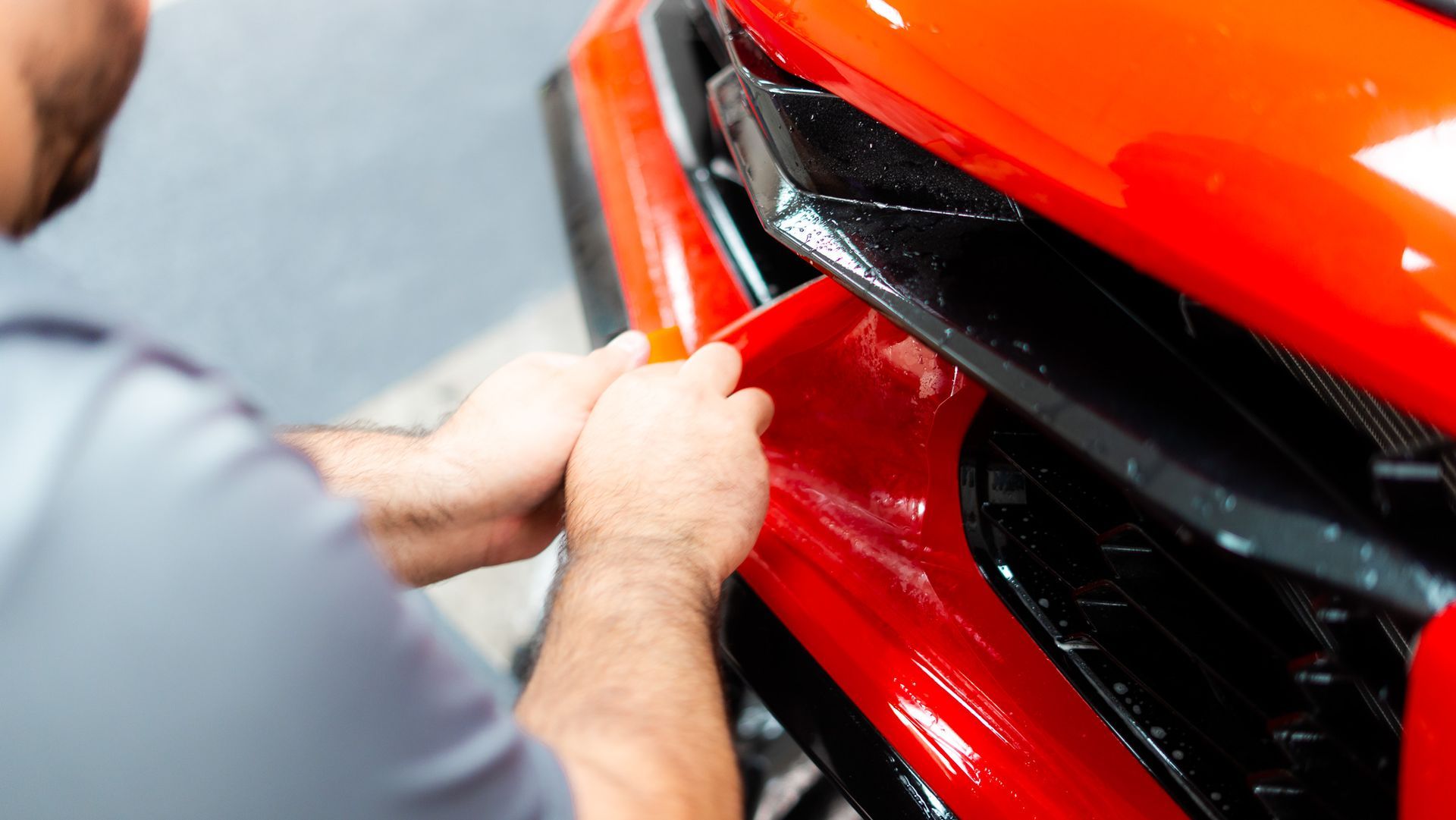 A man is working on the front of a car.