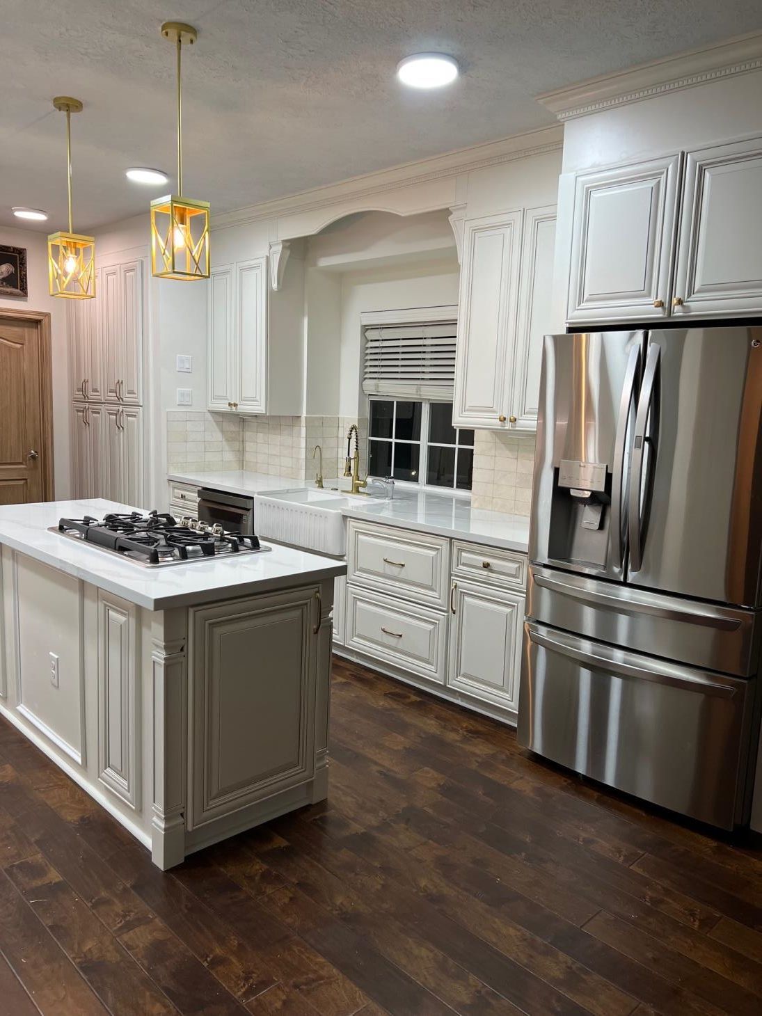 A kitchen with white cabinets , stainless steel appliances , and a large island.