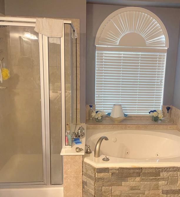 A bathroom with a jacuzzi tub , shower , and window.
