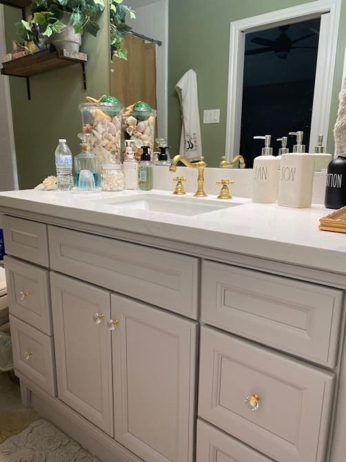 A bathroom with white cabinets , a sink and a mirror.