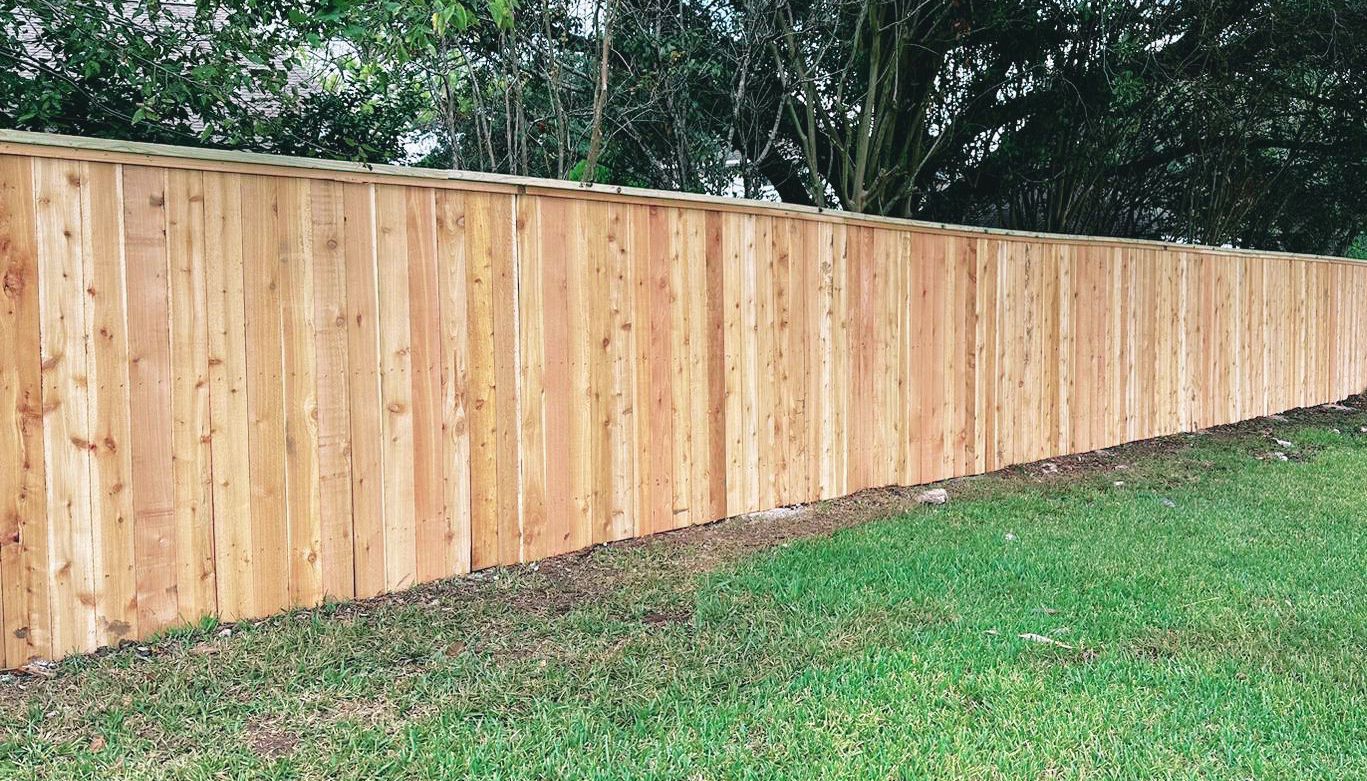 A wooden fence is sitting on top of a lush green lawn.