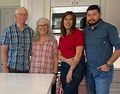 A family is posing for a picture in a kitchen.