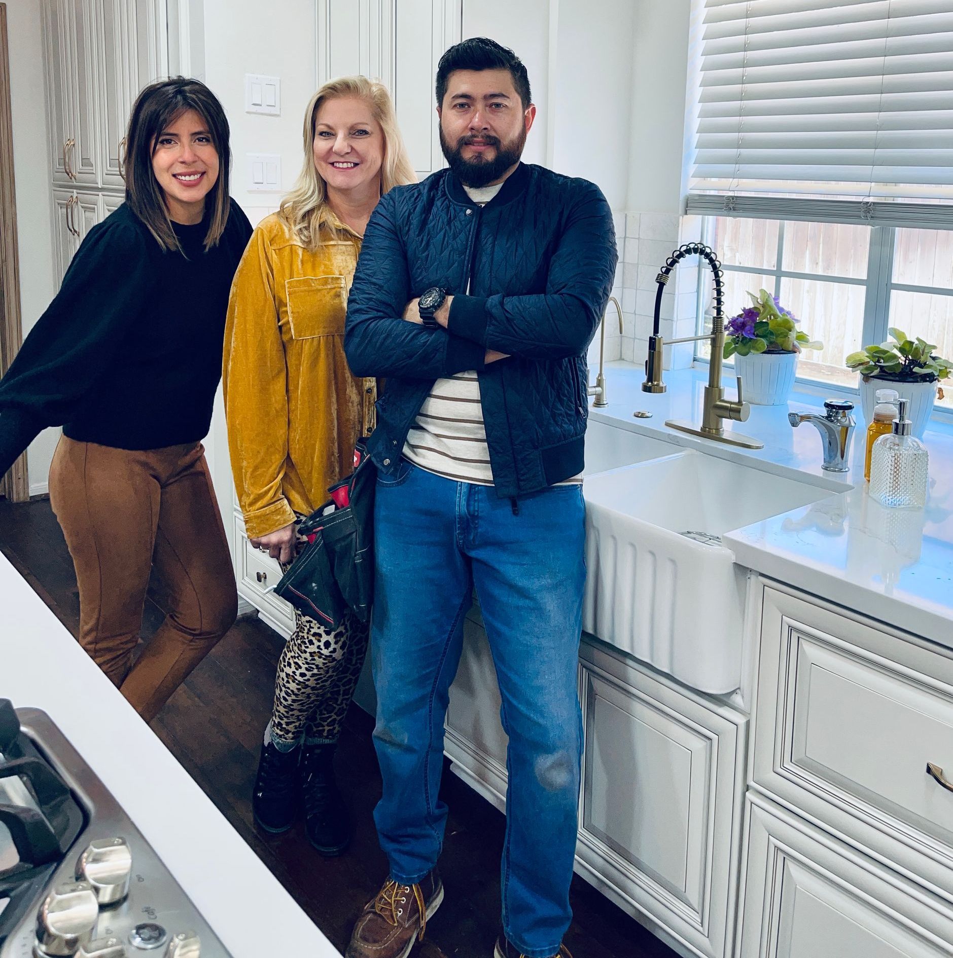A man and two women are posing for a picture in a kitchen.