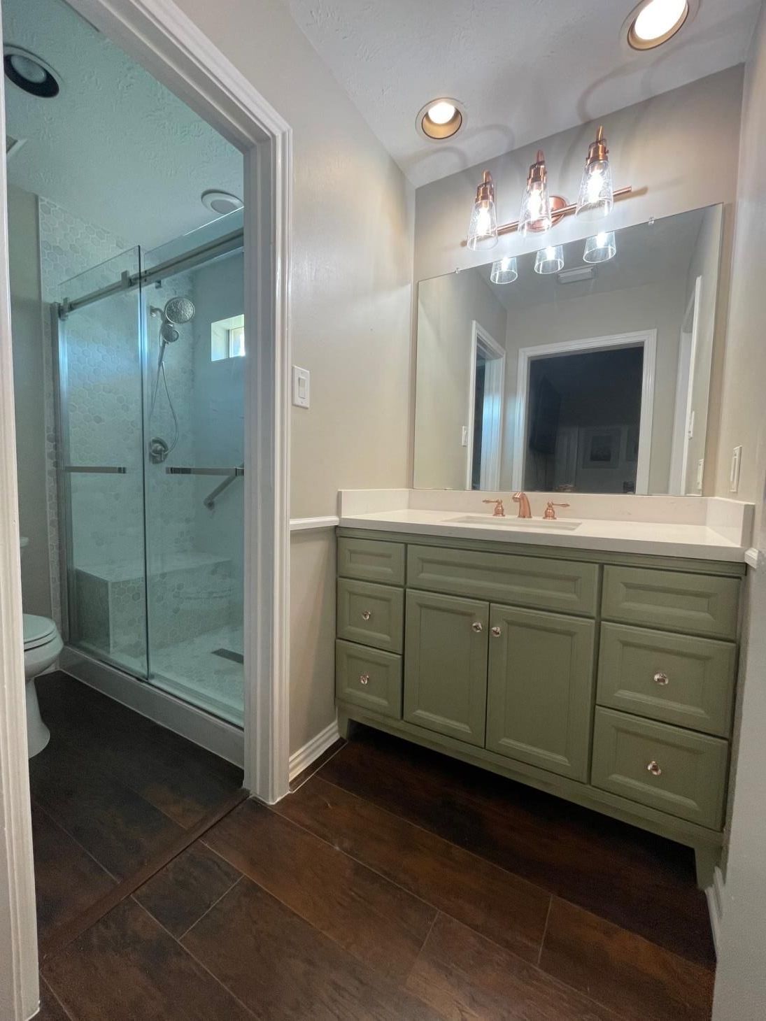 A bathroom with a sink , toilet , shower and mirror.