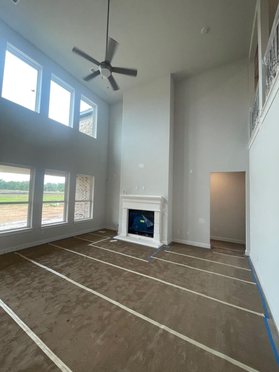 An empty living room with a fireplace and a ceiling fan.