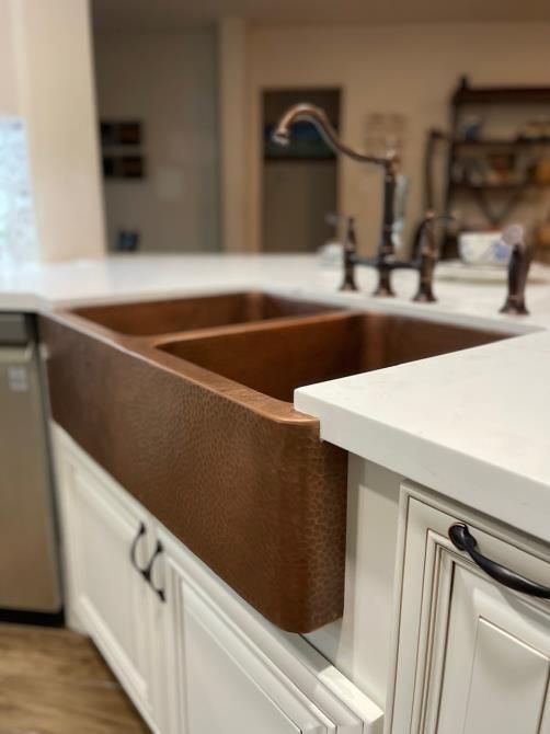 A kitchen with a copper sink and white cabinets