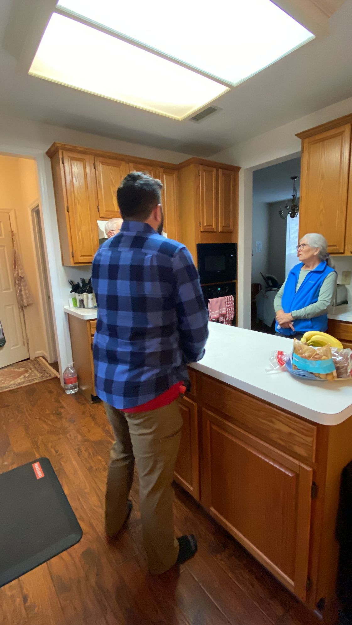 A man and a woman are standing in a kitchen talking to each other.