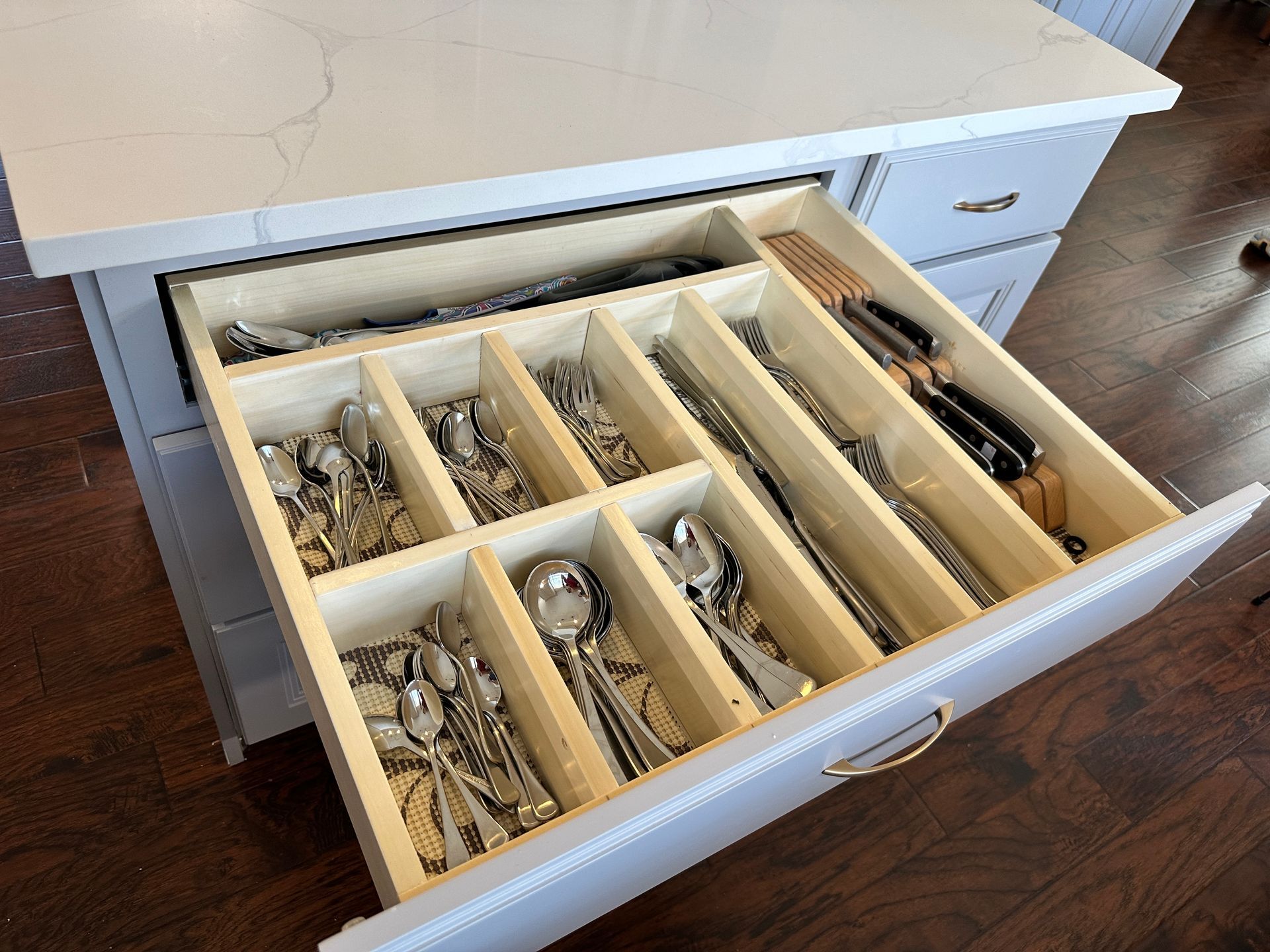 A kitchen drawer filled with silverware and knives.