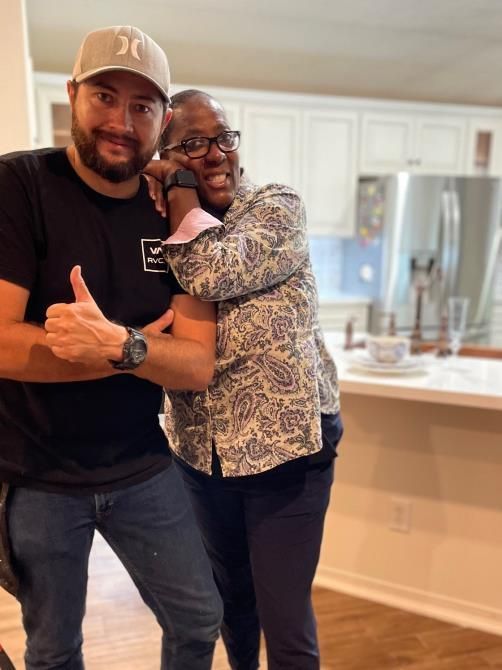 A man and a woman are posing for a picture in a kitchen.