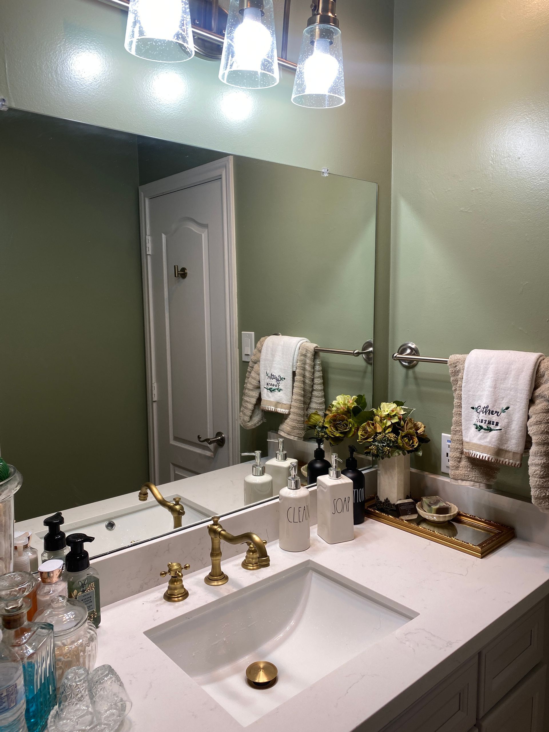 A bathroom with a sink , mirror and towels.