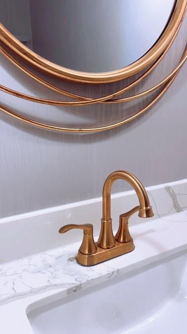 A bathroom sink with a gold faucet and a mirror above it.