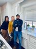 A man and two women are standing in a kitchen with their arms crossed.