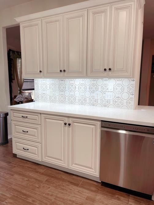 A kitchen with white cabinets and a stainless steel dishwasher.