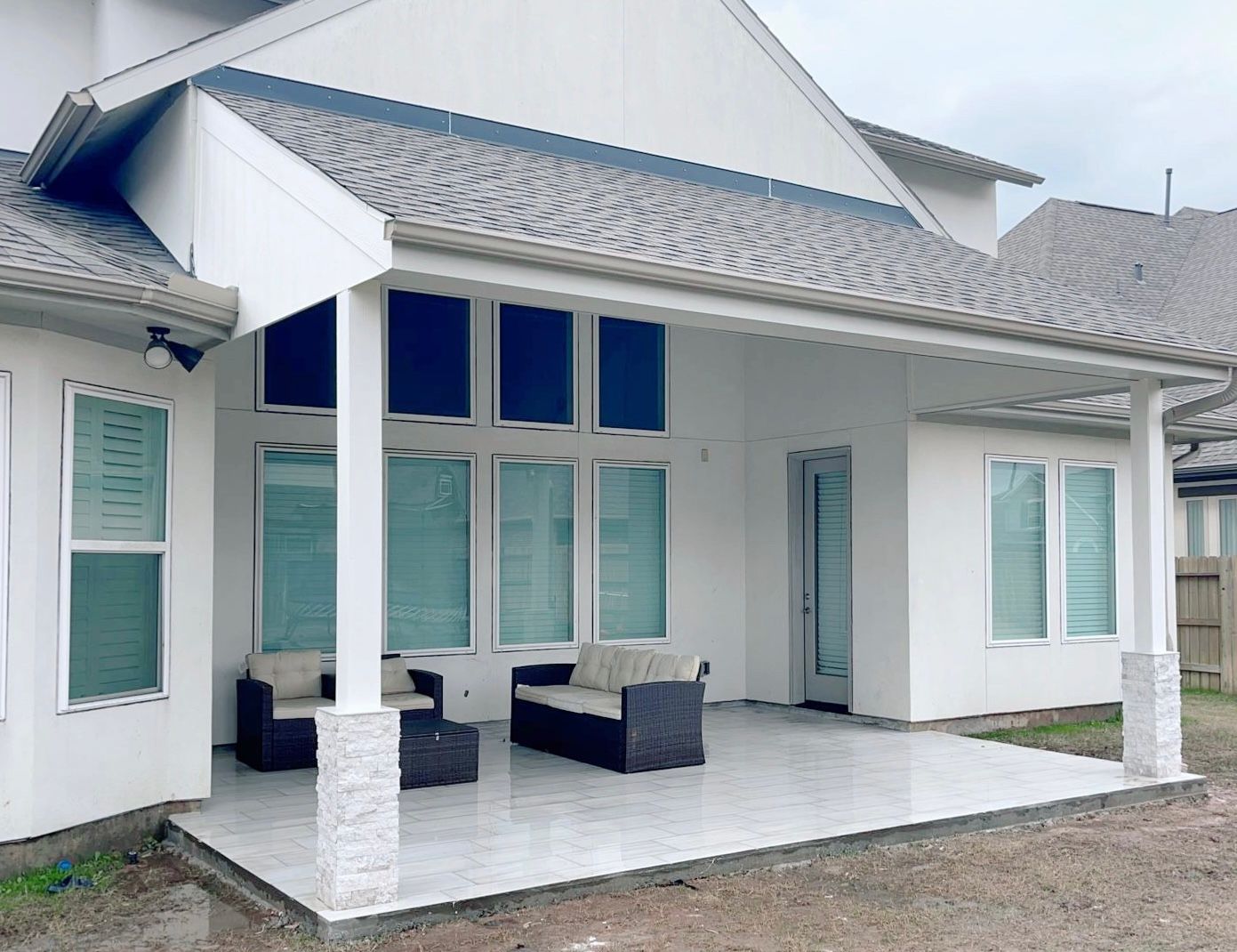 A white house with a covered porch and patio furniture