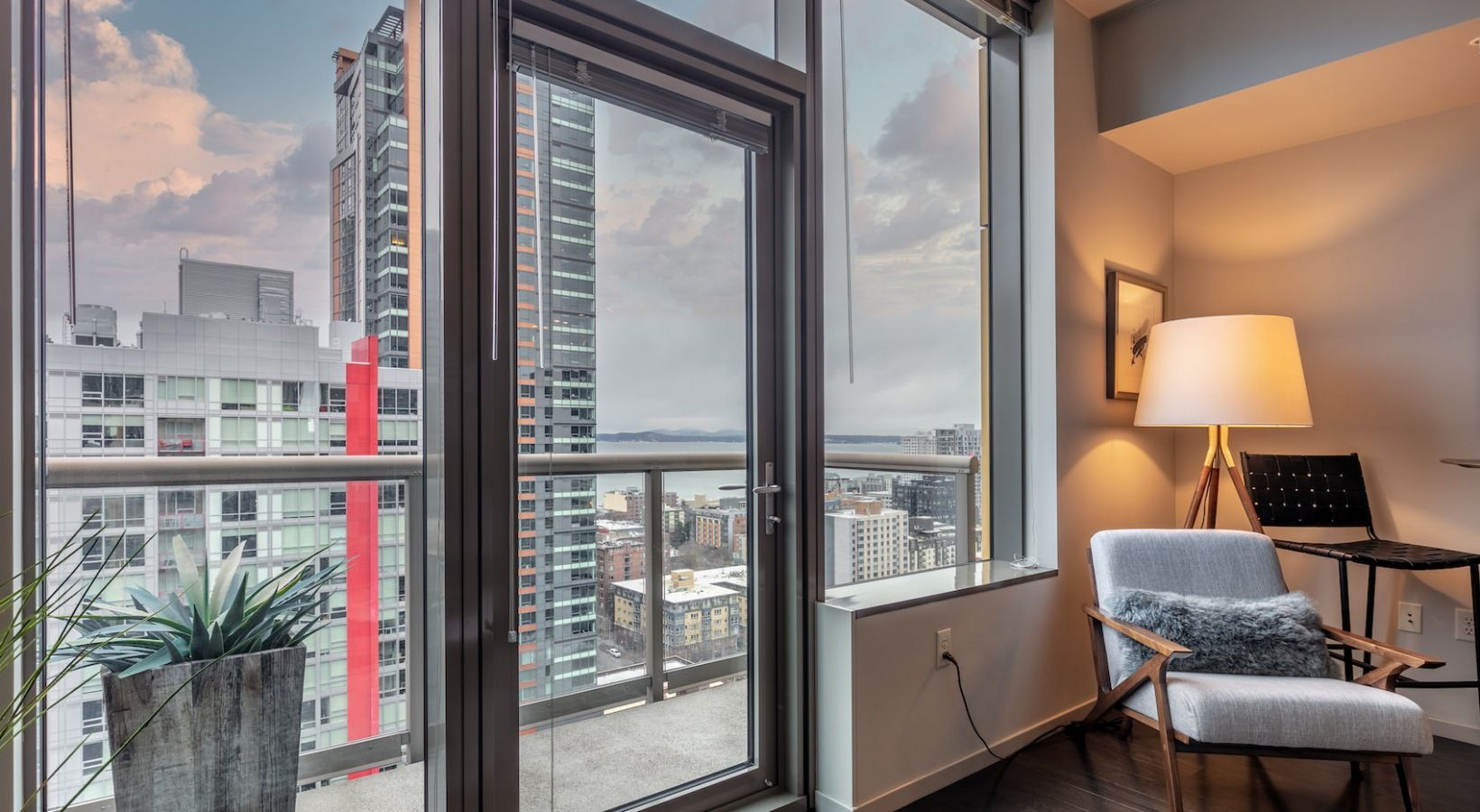 Modern apartment living room with a glass door to a balcony and city skyline view.