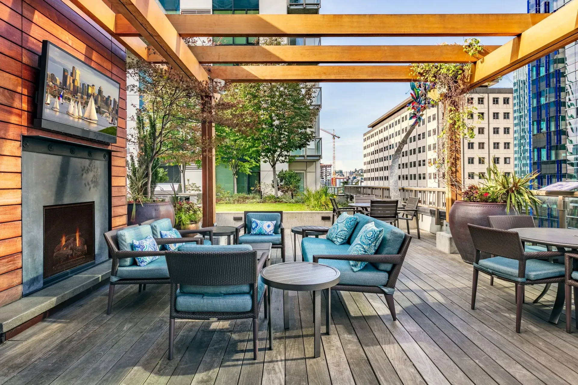 Outdoor rooftop lounge with seating, fireplace, and city view.
