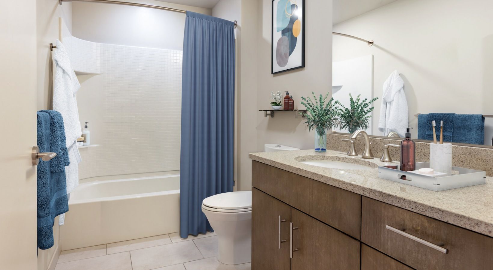Bathroom with a single vanity, tub/shower, and blue towels.