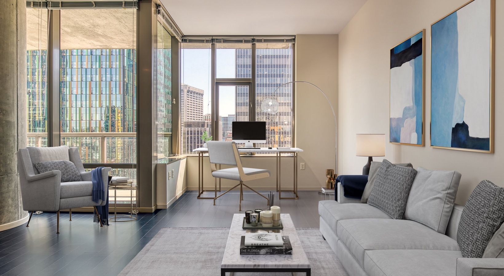Modern apartment living room with a desk, sofa, and large city-view windows.