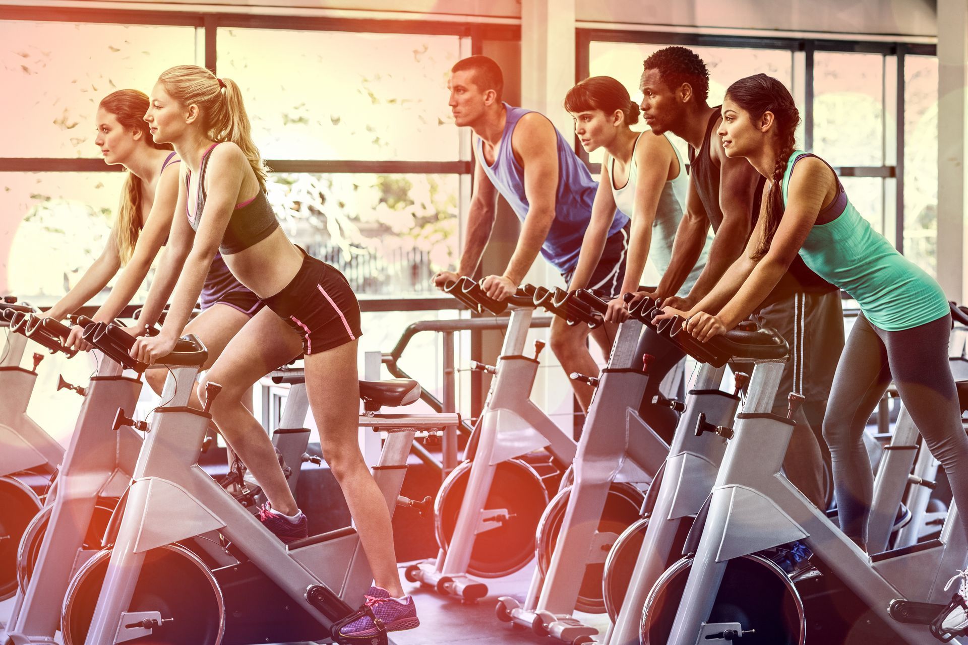 People in workout clothes on stationary bikes in a gym.