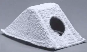 A white, textured triangular hideout cave for small pets, featuring a round entrance hole on the side.