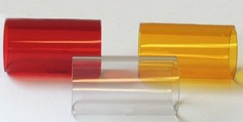 Three translucent, cylindrical plastic sleeves in red, clear, and yellow, arranged on a white surface.