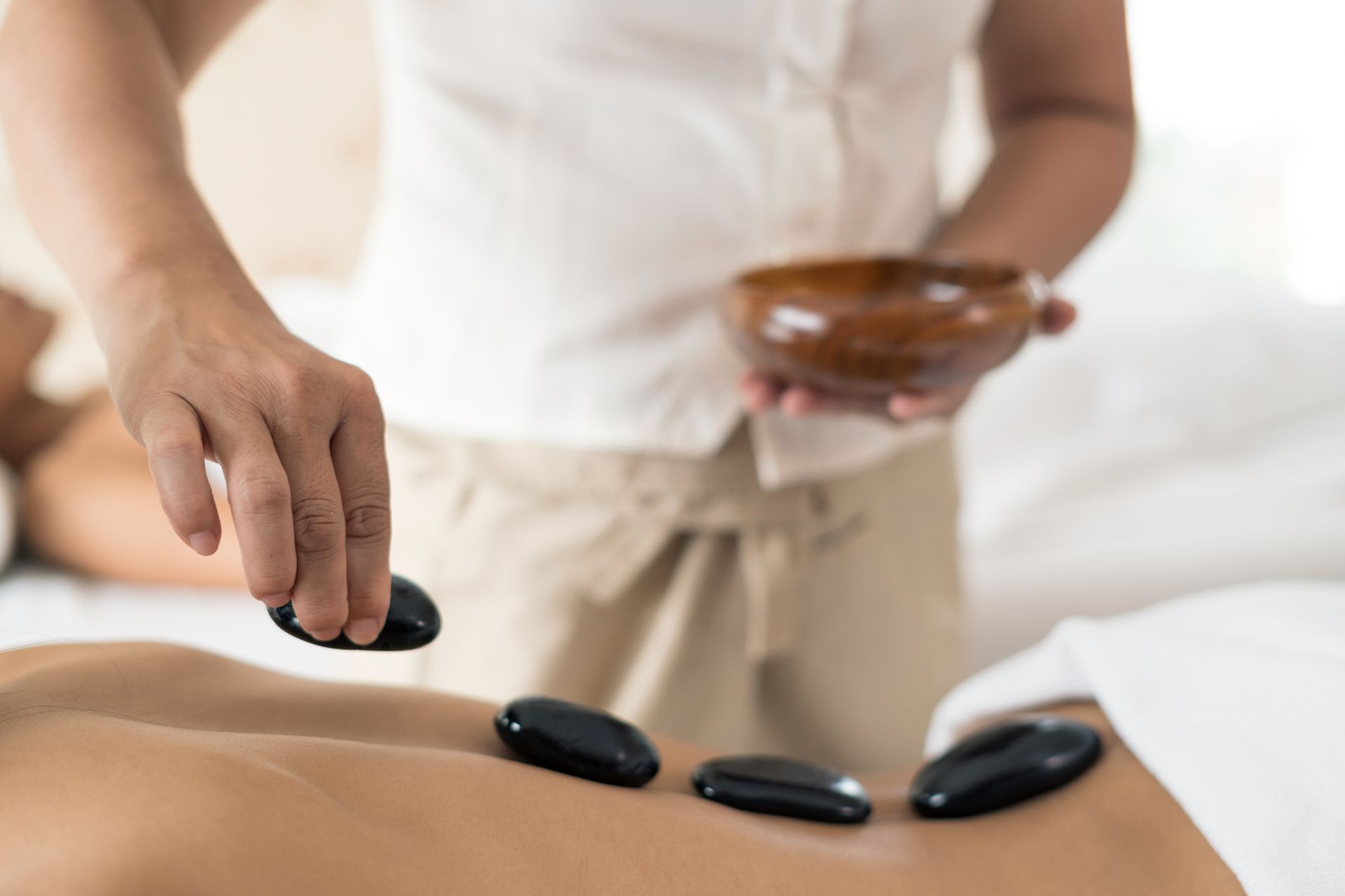 A Woman Is Getting A Hot Stone Massage At A Spa — Wilmington, NC — Mystic Massage