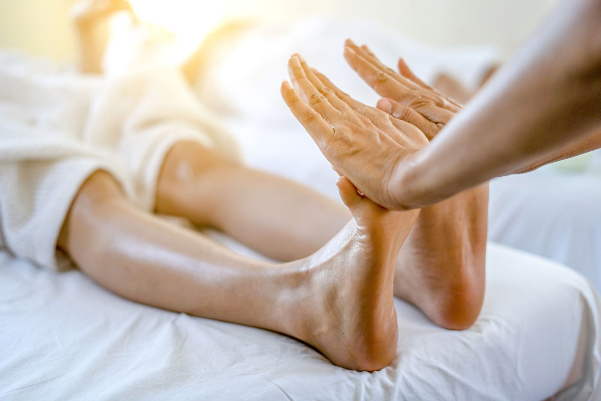 A Person Is Getting A Foot Massage On A Bed — Wilmington, NC — Mystic Massage