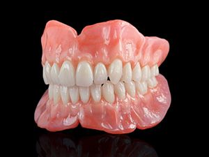 Dentist showing teeth model to patient in a bright dental office.